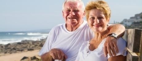 man and woman over 60 smiling at a beach