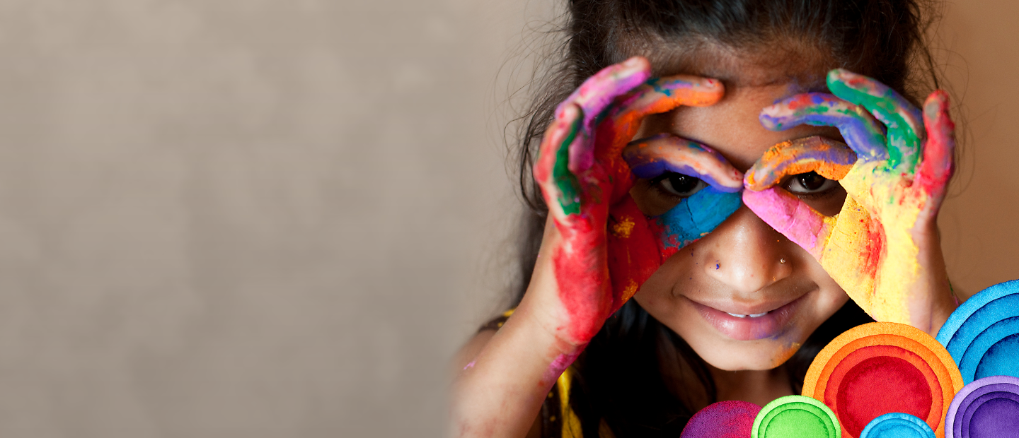 child finger painting while holding fingers to her face